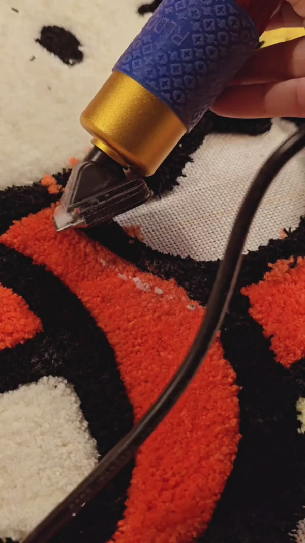 Carving EFFY cotton blend yarn on an orange cat rug, showing densely tufted yarn and a well-oiled blade.